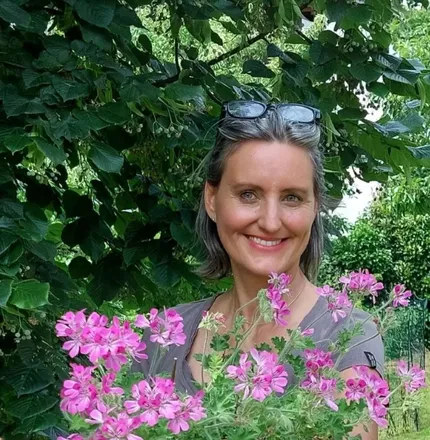Carmen Bewusstseinsgärtnerin Carmen, die Bewusstseinsgärtnerin, steht strahlend im Garten und hält einen wunderschönen rosa Blumenstrauß im Arm – ein Bild voller Herzenswärme und Naturverbundenheit.